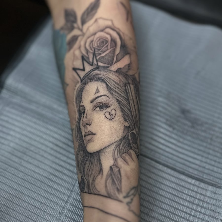 A delicate black and grey portrait of a woman with a crown and rose on the forearm — by Maddie Ramirez, los angeles