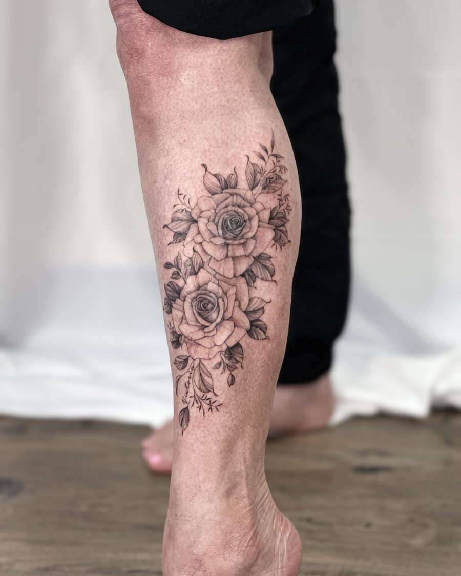 A delicate black and grey rose bouquet tattoo on the calf with fine line detailing and romantic shading — by Melanie Benoit, los angeles