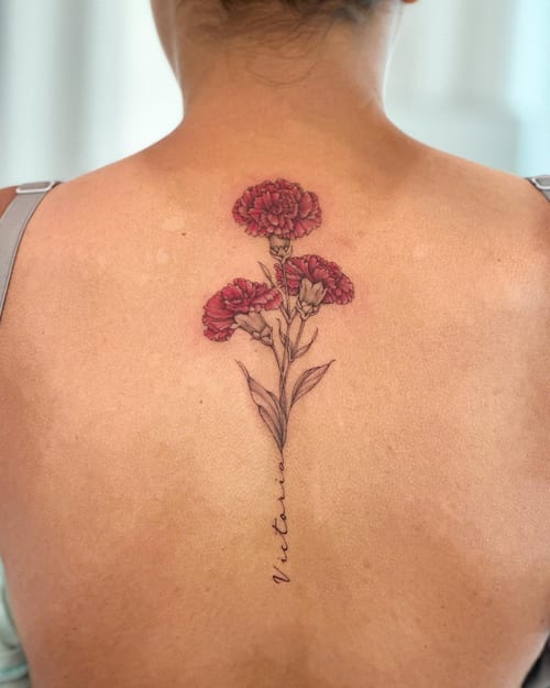 A delicate fine line tattoo of red carnations with a name in script on the back, featuring a romantic and botanical style — by Melanie Benoit, los angeles
