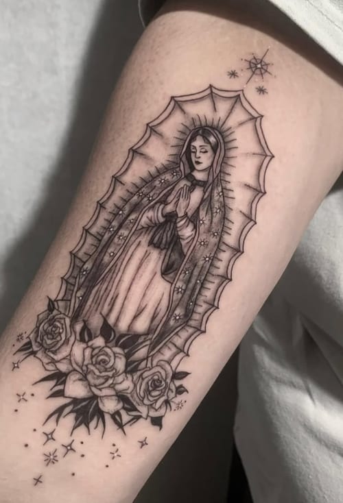 A black and grey fine line tattoo of the Virgin Mary surrounded by roses and stars on the upper arm, featuring delicate shading and intricate details — by Shelby Bianco, los angeles