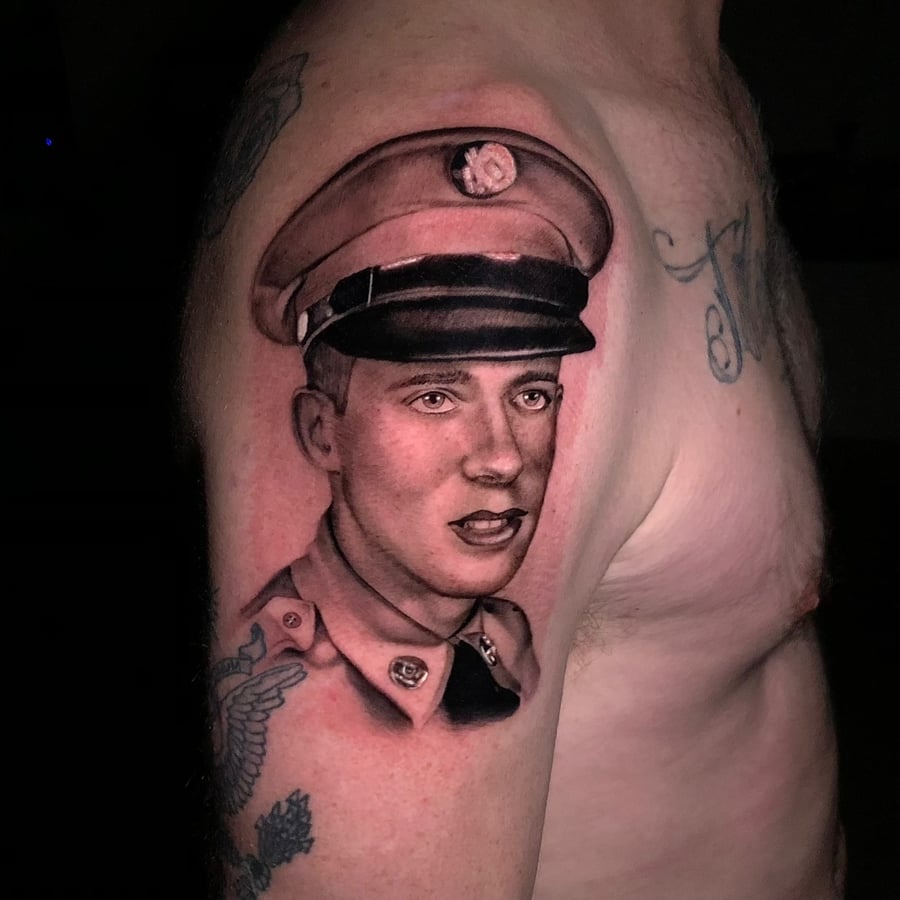 A black and grey realism portrait of a man in uniform on the upper arm, featuring detailed shading and lifelike features — by Travis Ross, los angeles