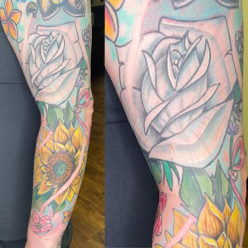 A colorful neo-traditional tattoo featuring a rose and sunflower on the arm, with bold outlines and vibrant colors — by Sandra Price, los angeles
