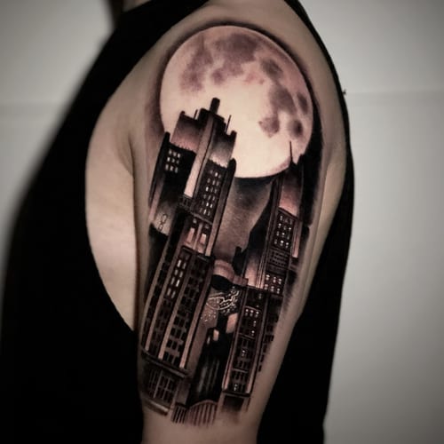 A black and grey realism tattoo of a cityscape under a full moon on the upper arm, featuring detailed buildings and soft shading — by Travis Ross, los angeles