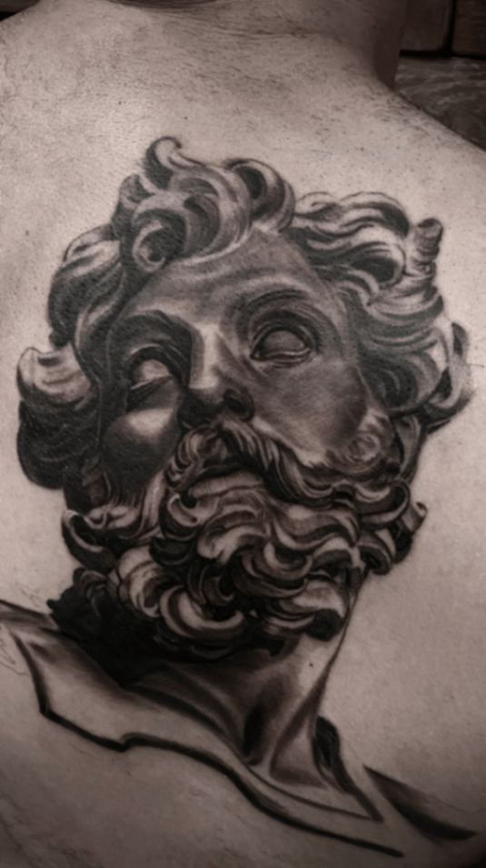 A black and grey realism portrait of Zeus on the back, featuring detailed shading and intricate hair and beard — by tyler_whitlock, los angeles