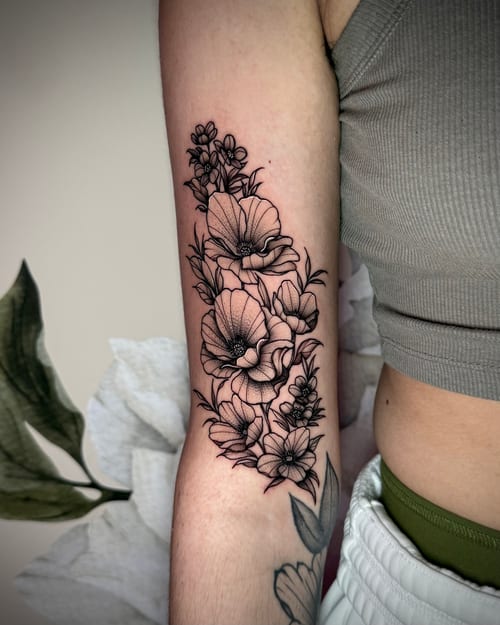 A black and grey fine line floral tattoo on the forearm, featuring detailed flowers with delicate linework — by emily, los angeles