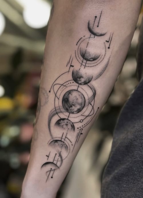 A black and grey tattoo on the forearm depicting the phases of the moon with geometric and dotwork elements — by Jian Liang, los angeles