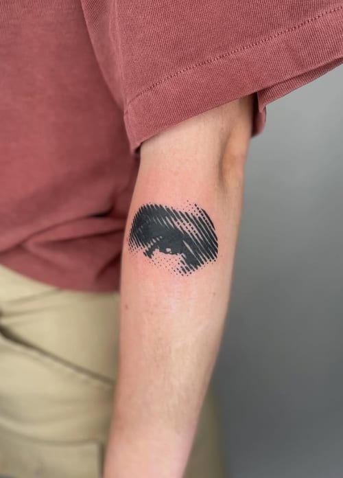 A black and grey abstract tattoo of an eye on the forearm, featuring bold black lines and shading — by Level tattoo, los angeles