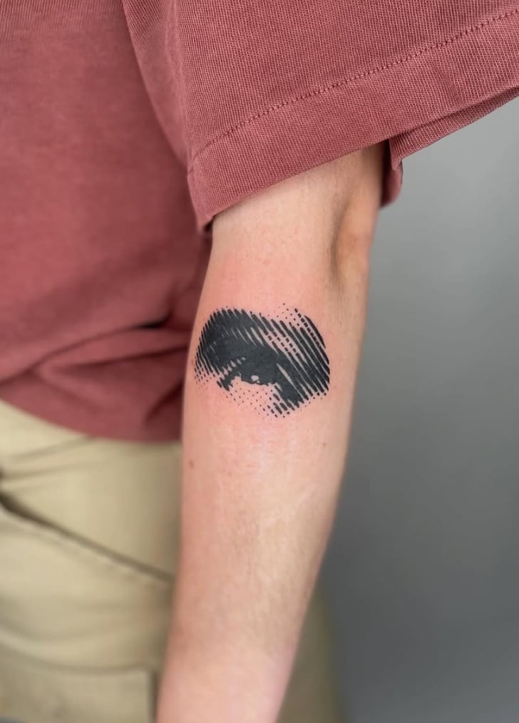 A black and grey abstract tattoo of an eye on the forearm, featuring bold black lines and shading — by Level tattoo, los angeles