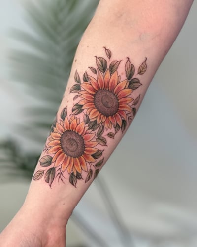 A colorful illustrative sunflower tattoo on the forearm with delicate floral details — by Melanie Benoit, los angeles