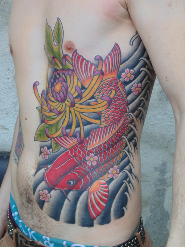 A colorful Japanese style tattoo of a koi fish and chrysanthemum on the side of the body — by Samuel Connelly, san diego, ca