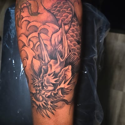 A black and grey Japanese-style dragon tattoo on the leg, featuring intricate scales and dynamic lines — by Dretty, los angeles