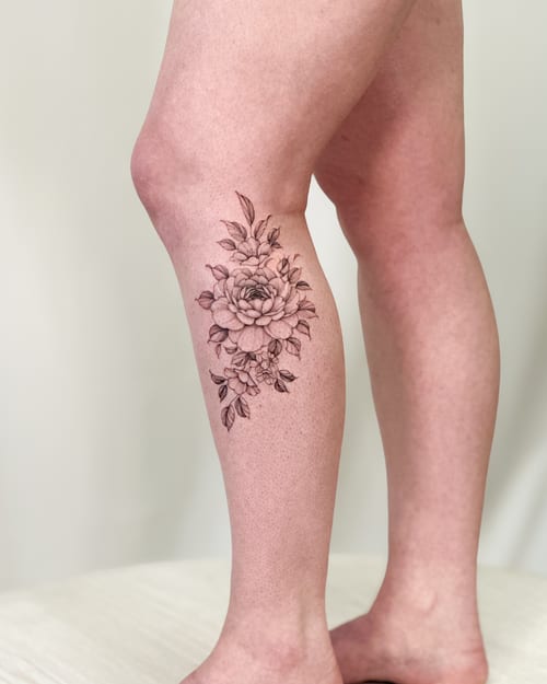 A delicate black and grey fine line flower bouquet tattoo on the leg, featuring intricate floral details — by Melanie Benoit, los angeles