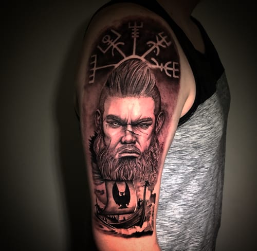 A black and grey realism tattoo of a Viking warrior on the upper arm, featuring detailed facial features and Norse symbols — by Travis Ross, los angeles