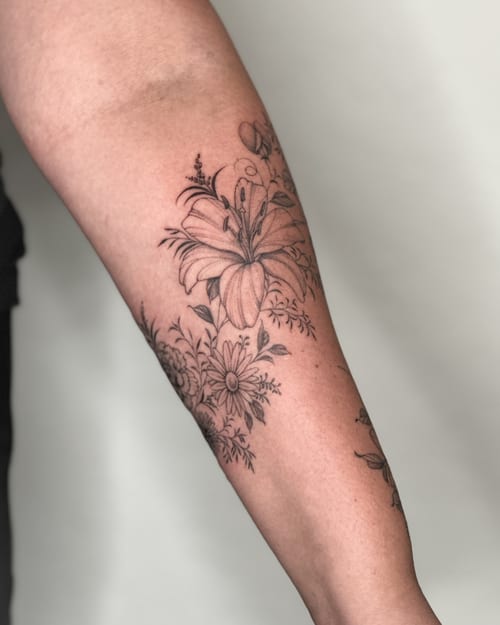 A delicate black and grey floral bouquet tattoo on the forearm, featuring fine line work and clean detailing — by Melanie Benoit, los angeles