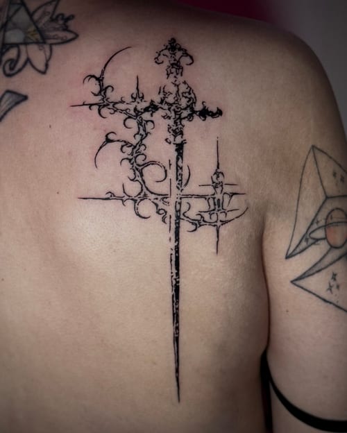 A black and grey ornamental sword tattoo on the back with intricate detailing and sharp lines — by emily, los angeles