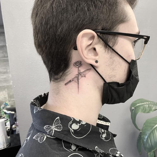 A delicate black and grey tattoo of a rose and knife on the neck, done in a fine line minimalist style — by Jian Liang, los angeles