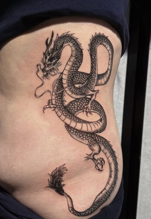 A detailed black and grey dragon tattoo on the rib, featuring intricate scales and flowing lines in a Japanese style — by Shelby Bianco, los angeles