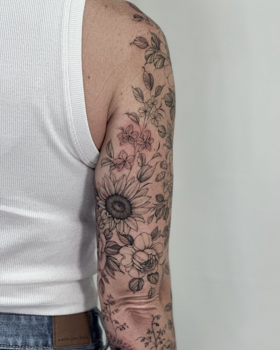 A delicate black and grey floral arrangement tattoo on the arm featuring various flowers in a fine line style — by Melanie Benoit, los angeles