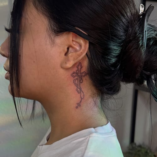 A delicate fine line cross with a rosary tattooed on the neck, featuring a minimalist design in black and grey — by NJ TATTOOZ, los angeles