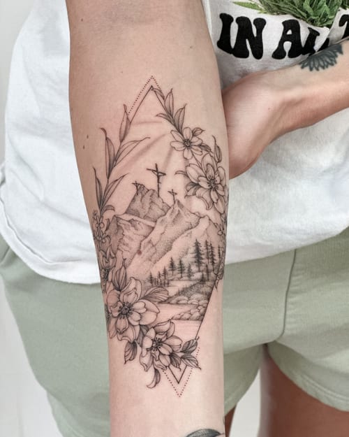 A delicate black and grey mountain landscape with flowers on the forearm, featuring fine line work and clean detailing — by Melanie Benoit, los angeles