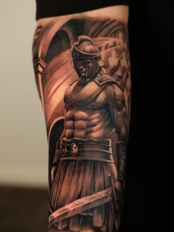 A realistic black and grey tattoo of a Roman soldier on the forearm, featuring detailed armor and a sword — by Johnny Ayala, fontana, ca