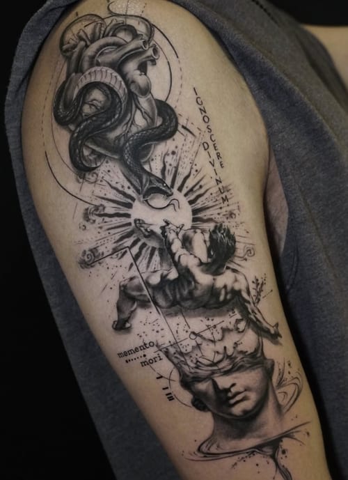A black and grey surrealistic tattoo on the upper arm featuring a snake, an angel, and script elements with intricate linework and shading — by Jian Liang, los angeles