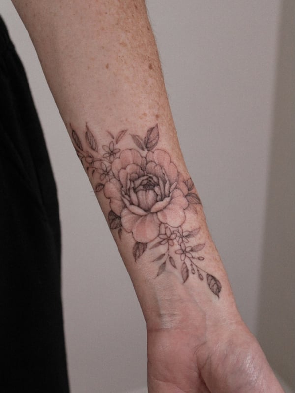 A delicate black and grey floral bouquet tattoo on the forearm, featuring fine line work and intricate details — by Melanie Benoit, los angeles