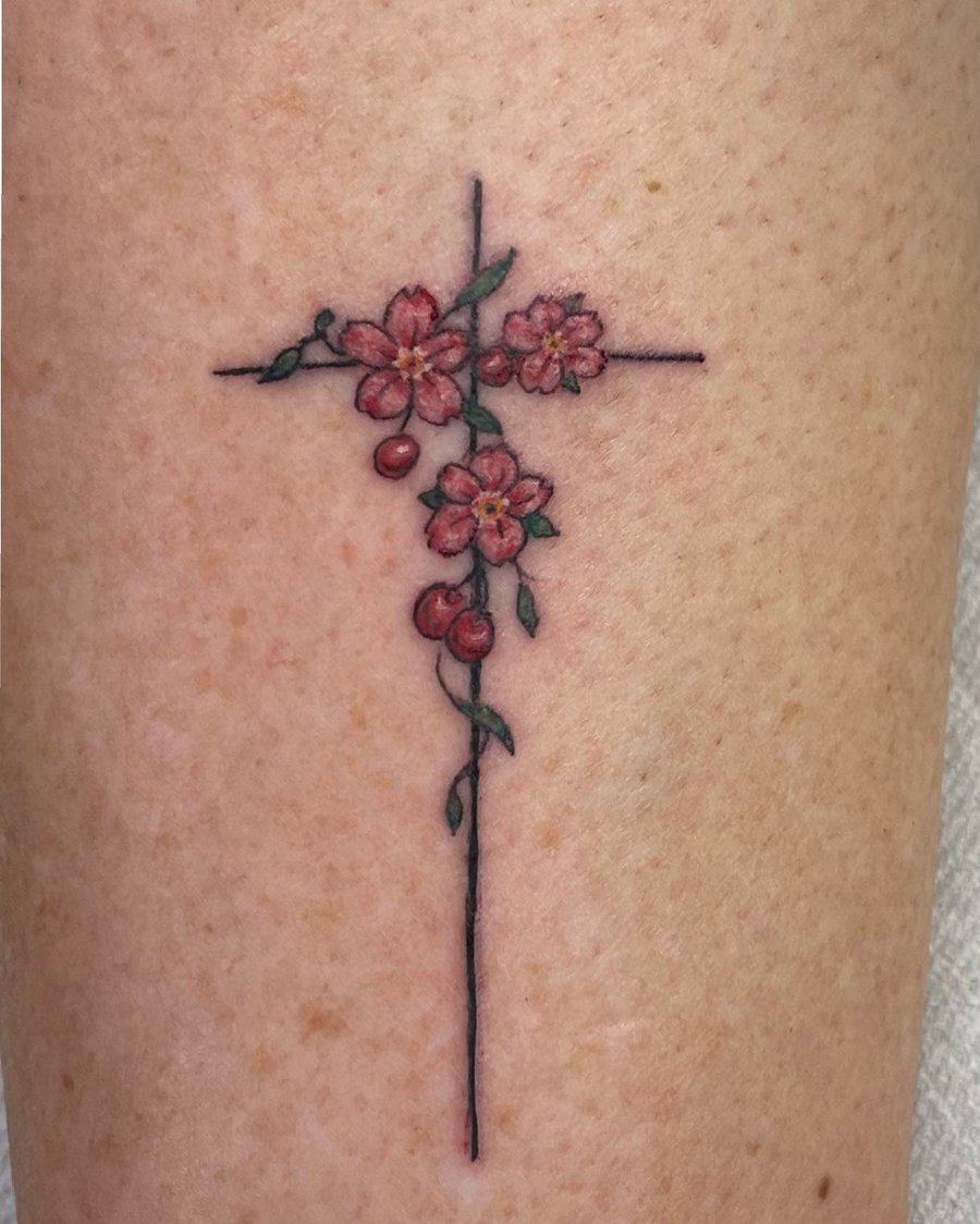 A delicate fine line cross with flowers on the forearm, featuring a minimalist and colorful design — by Sandra Price, los angeles