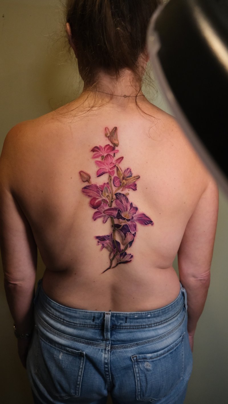 color realism tattoo of magenta orchids trailing down the spine by nik lucas, a realism tattoo artist in mid-city, los angeles