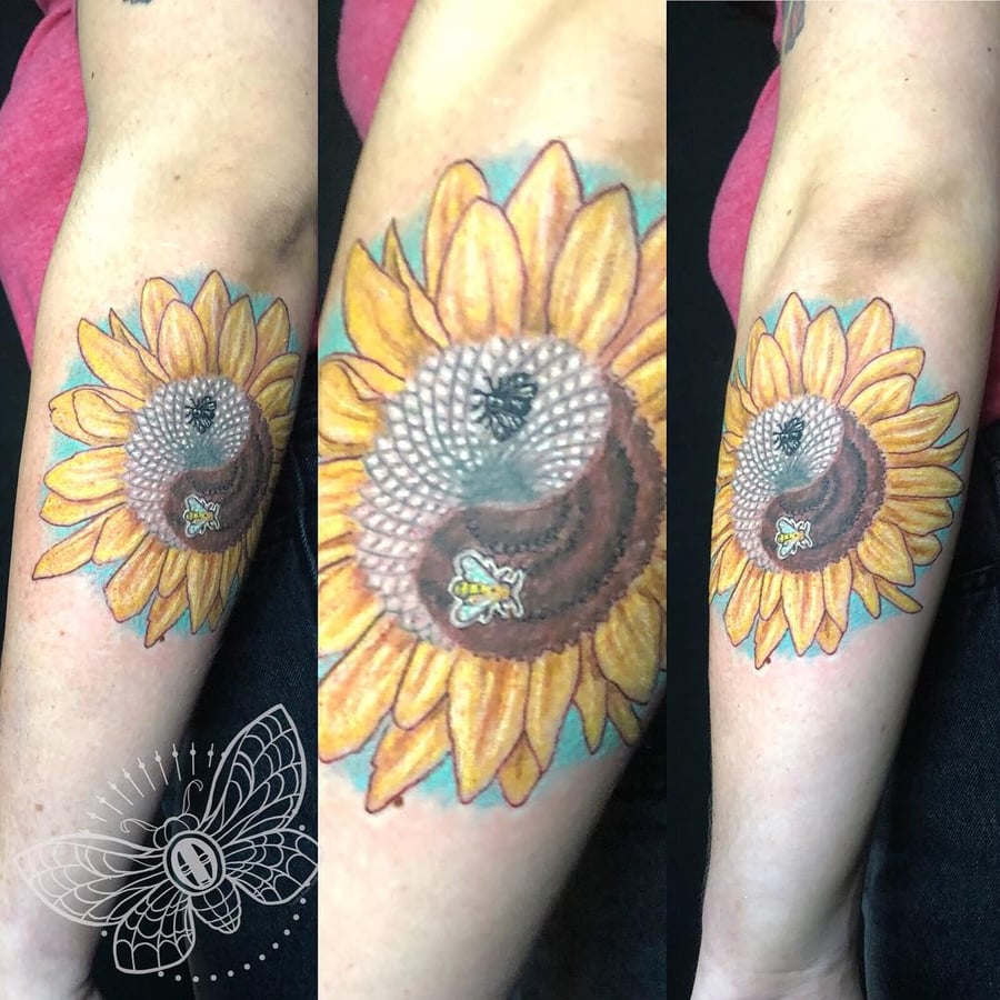 A colorful illustrative tattoo of a sunflower with a yin yang symbol and bees on the forearm — by Sandra Price, los angeles
