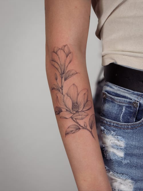 A delicate black and grey fine line flower branch tattoo on the forearm — by Melanie Benoit, los angeles