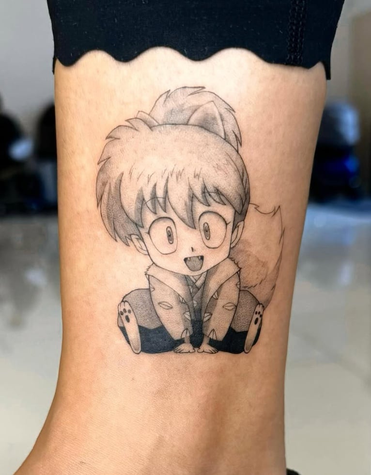 A black and grey anime-style tattoo of a character with large eyes and a playful expression on the ankle — by otaybeatdown, los angeles