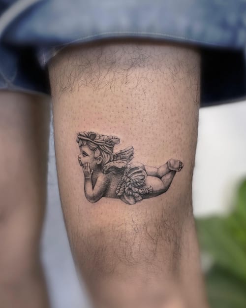 A delicate black and grey cherub tattoo on the thigh, featuring realistic shading and detail — by Jian Liang, los angeles