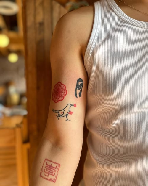A minimalist bird and abstract designs tattoo on the upper arm, featuring linework and color elements — by Dylan Aiello, los angeles