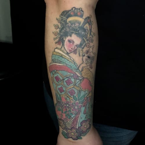A colorful Japanese-style tattoo of a geisha with a cat on the forearm, featuring ornate floral patterns — by Sandra Price, los angeles