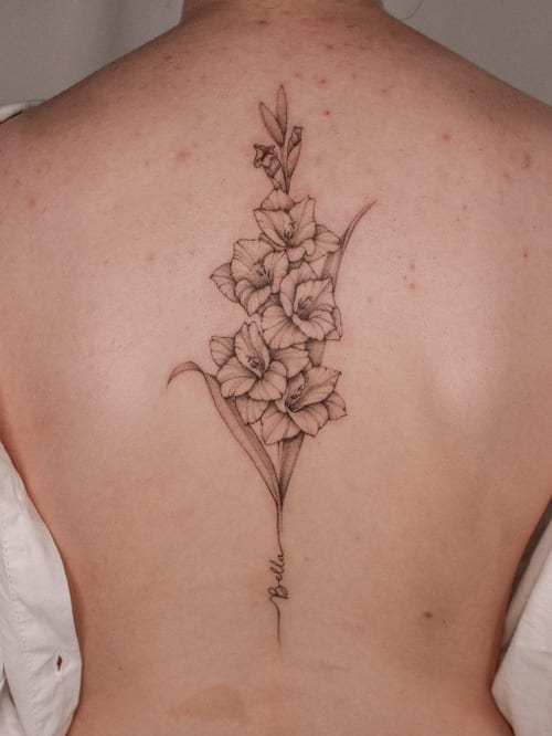 A delicate black and grey fine line tattoo of gladiolus flowers on the back, showcasing intricate floral details — by Melanie Benoit, los angeles