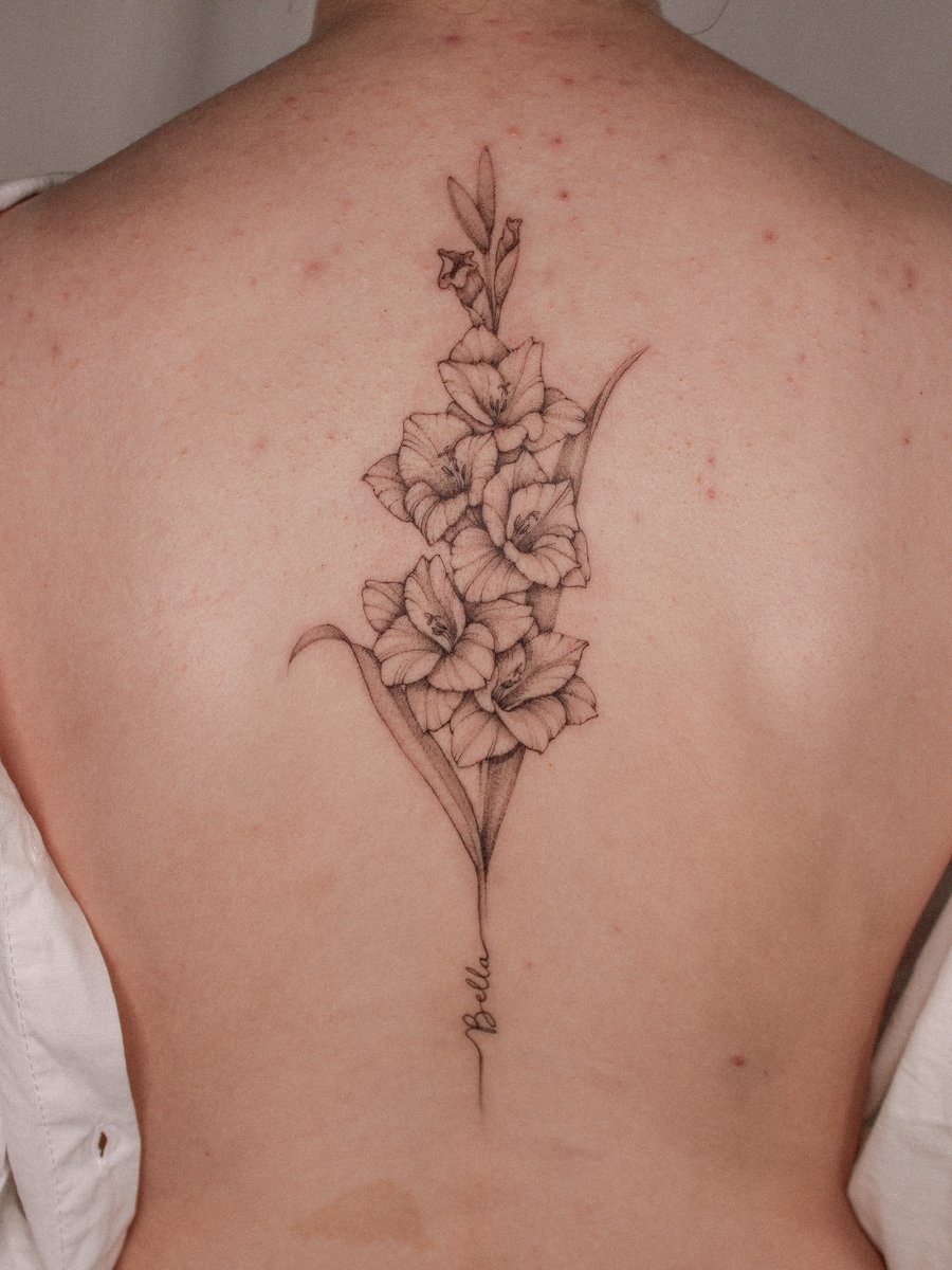 A delicate black and grey fine line tattoo of gladiolus flowers on the back, showcasing intricate floral details — by Melanie Benoit, los angeles