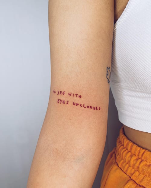 A minimalist script lettering tattoo on the arm with the phrase 'to see with eyes unclouded' in black ink — by Level tattoo, los angeles