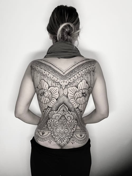 An intricate blackwork ornamental tattoo covering the full back, featuring mandala patterns and floral elements with detailed linework — by INKEDBy_G, los angeles