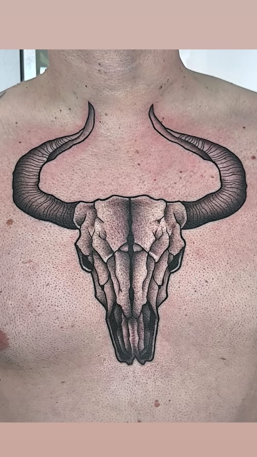 A bold black and grey bull skull tattoo on the chest with detailed linework — by Samuel Connelly, los angeles