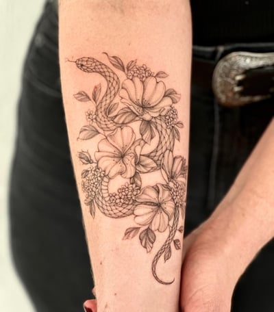 A delicate black and grey tattoo of a snake intertwined with flowers on the forearm, done in a fine line style — by Melanie Benoit, los angeles
