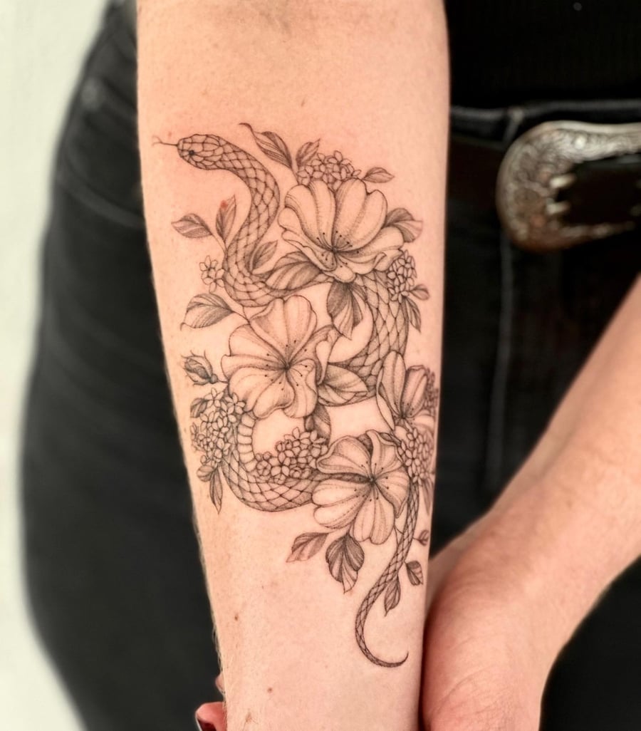 A delicate black and grey tattoo of a snake intertwined with flowers on the forearm, done in a fine line style — by Melanie Benoit, los angeles