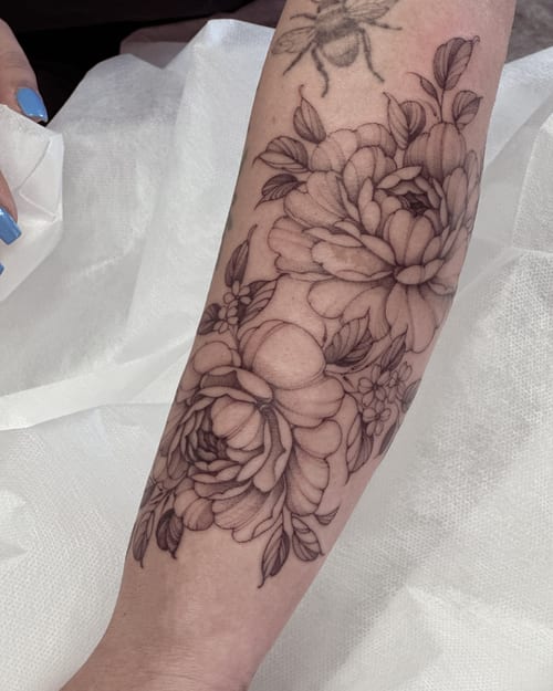 A delicate black and grey floral tattoo on the forearm with fine line detailing and clean shading — by Melanie Benoit, los angeles