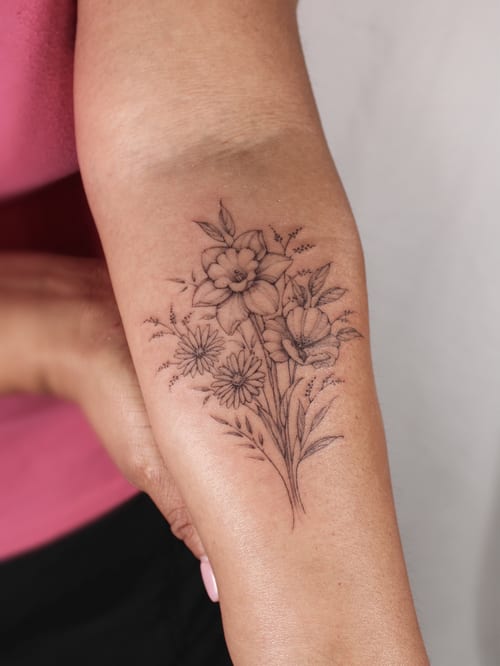 A delicate black and grey floral bouquet tattoo on the forearm, featuring fine line details — by Melanie Benoit, los angeles