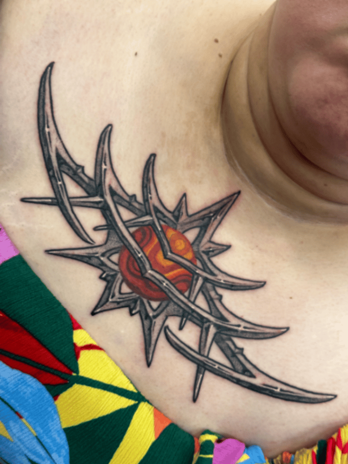 A colorful abstract tattoo on the chest featuring a stylized heart surrounded by tribal-like barbed elements — by tyler_whitlock, los angeles