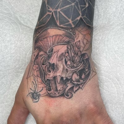 A black and grey tattoo of an animal skull with crystals and a mushroom on the hand, featuring intricate details and shading — by Sandra Price, los angeles