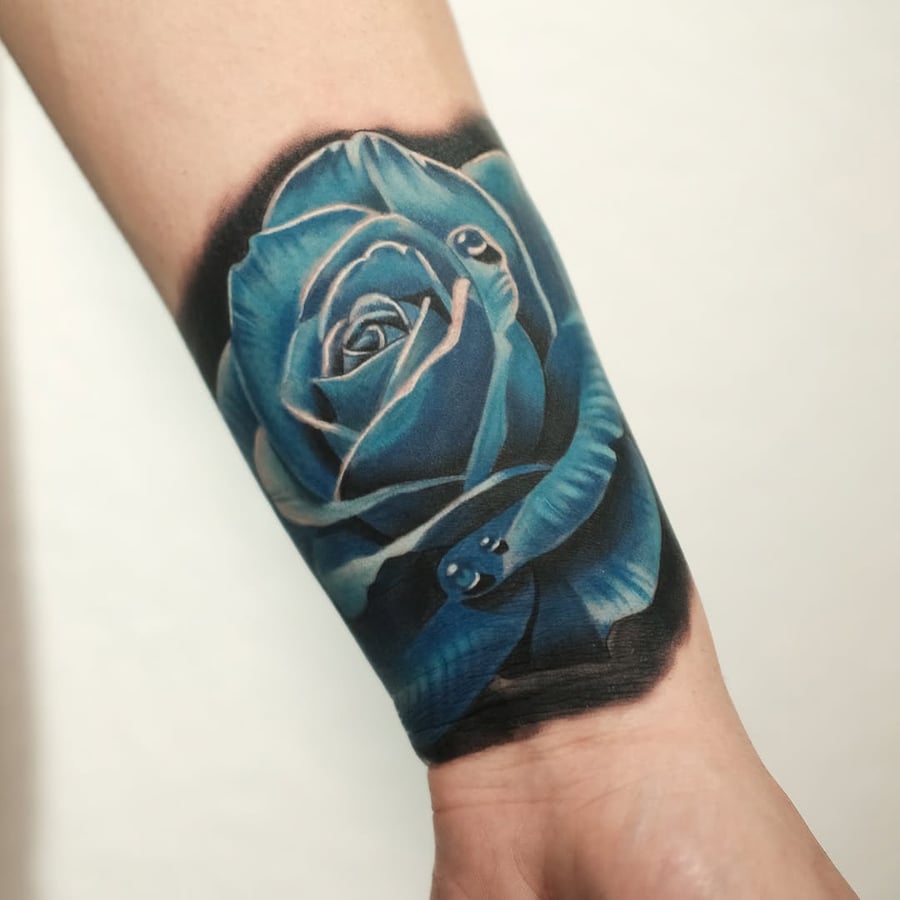 A bold and colorful tattoo of a blue rose with a snake wrapped around it on the forearm, done in a realistic style — by Johnny Ayala, los angeles