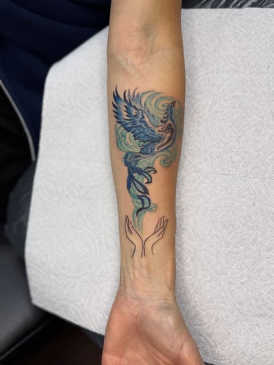 A colorful watercolor phoenix tattoo on the forearm with delicate and whimsical design elements — by Sandra Price, los angeles