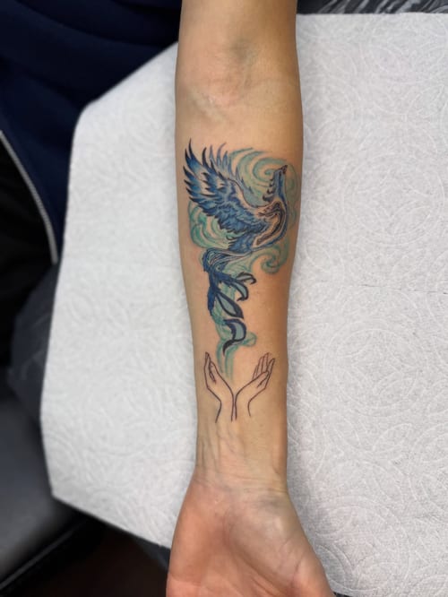 A colorful watercolor phoenix tattoo on the forearm with delicate and whimsical design elements — by Sandra Price, los angeles