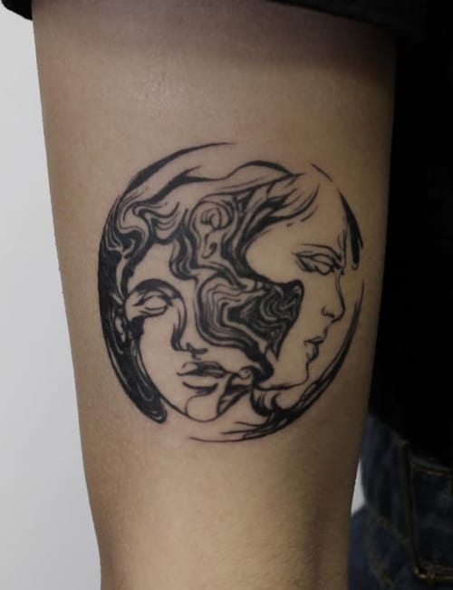 An abstract black and grey linework tattoo of two faces intertwined on the upper arm, featuring flowing lines and intricate details — by Jian Liang, los angeles